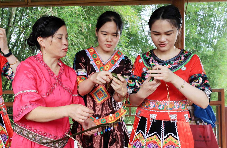 壮族姑娘正在学习包五彩粽子。
