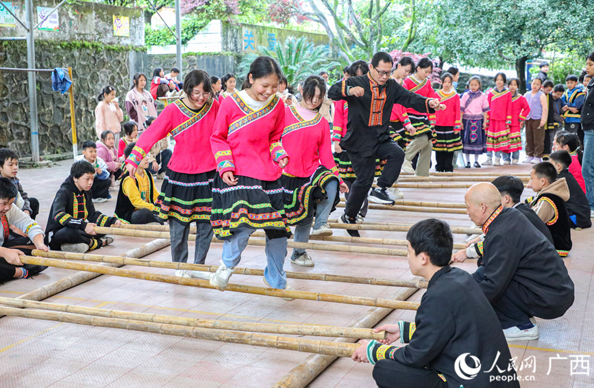 瑶乡的老师和学生们身着民族服饰跳竹竿舞。人民网记者 陈燕摄